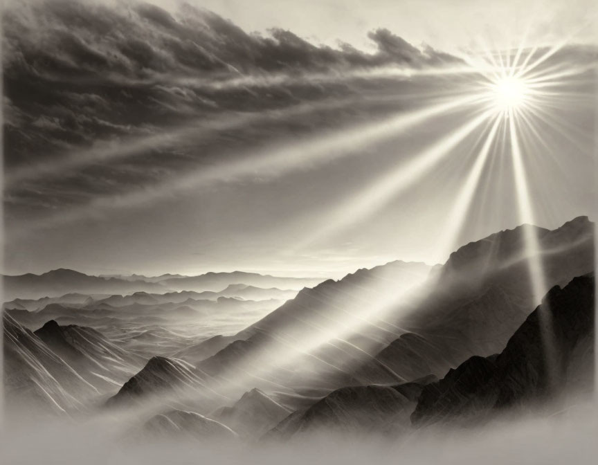 Sunbeams through cloudy skies illuminate layered mountain ridges