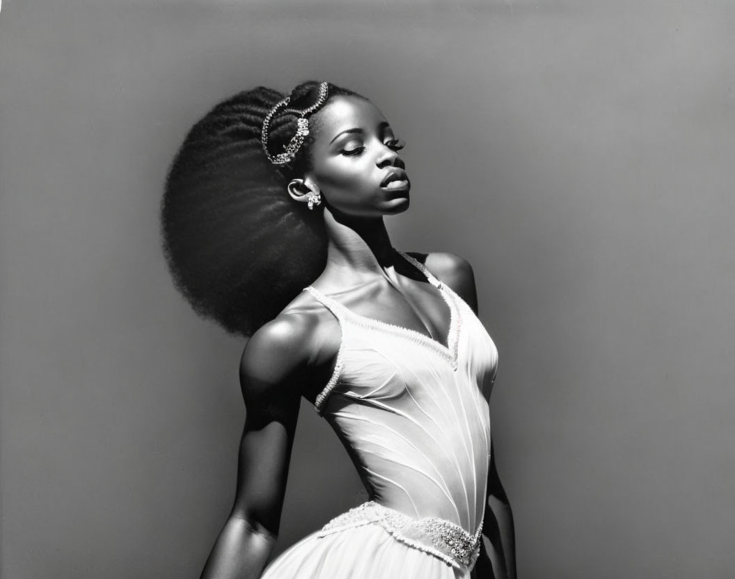 Monochrome portrait of poised woman with striking afro hair and elegant accessories