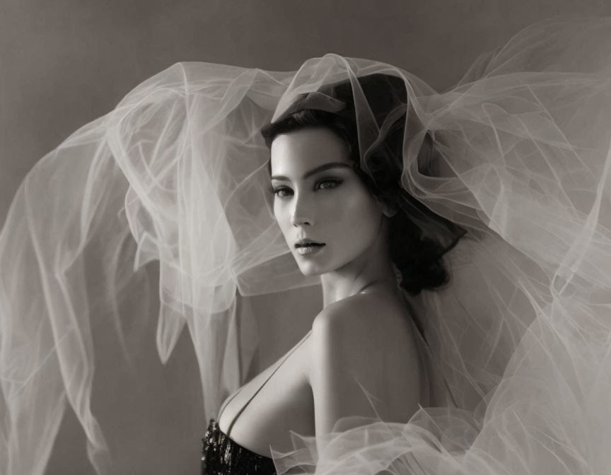 Monochrome portrait of woman in tulle fabric with intense gaze