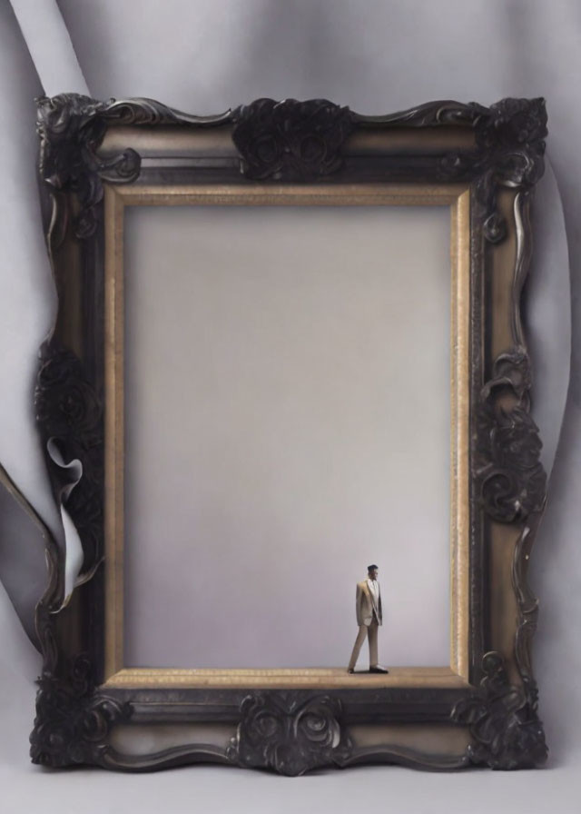 Miniature man figurine in suit inside ornate picture frame with draped backdrop