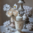 Vintage still life: Tarnished metal urn, white roses, assorted flowers, candlestick on sh