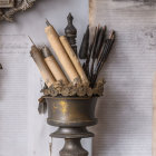 Vintage cup with rolls of paper and quills on script wallpaper, ship painting backdrop