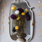 Vintage mirror reflecting colorful vase and flowers on gray wall with golden floral patterns