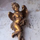 Bronze cherubic angel sculpture with wings and floral garland on textured wall