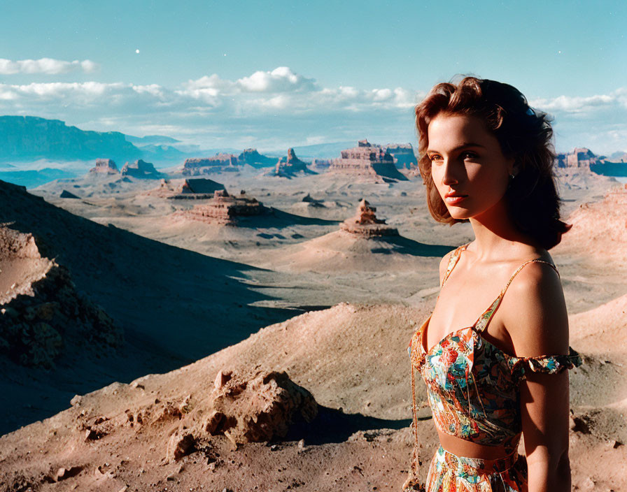 Woman in floral outfit against desert mesas under blue sky