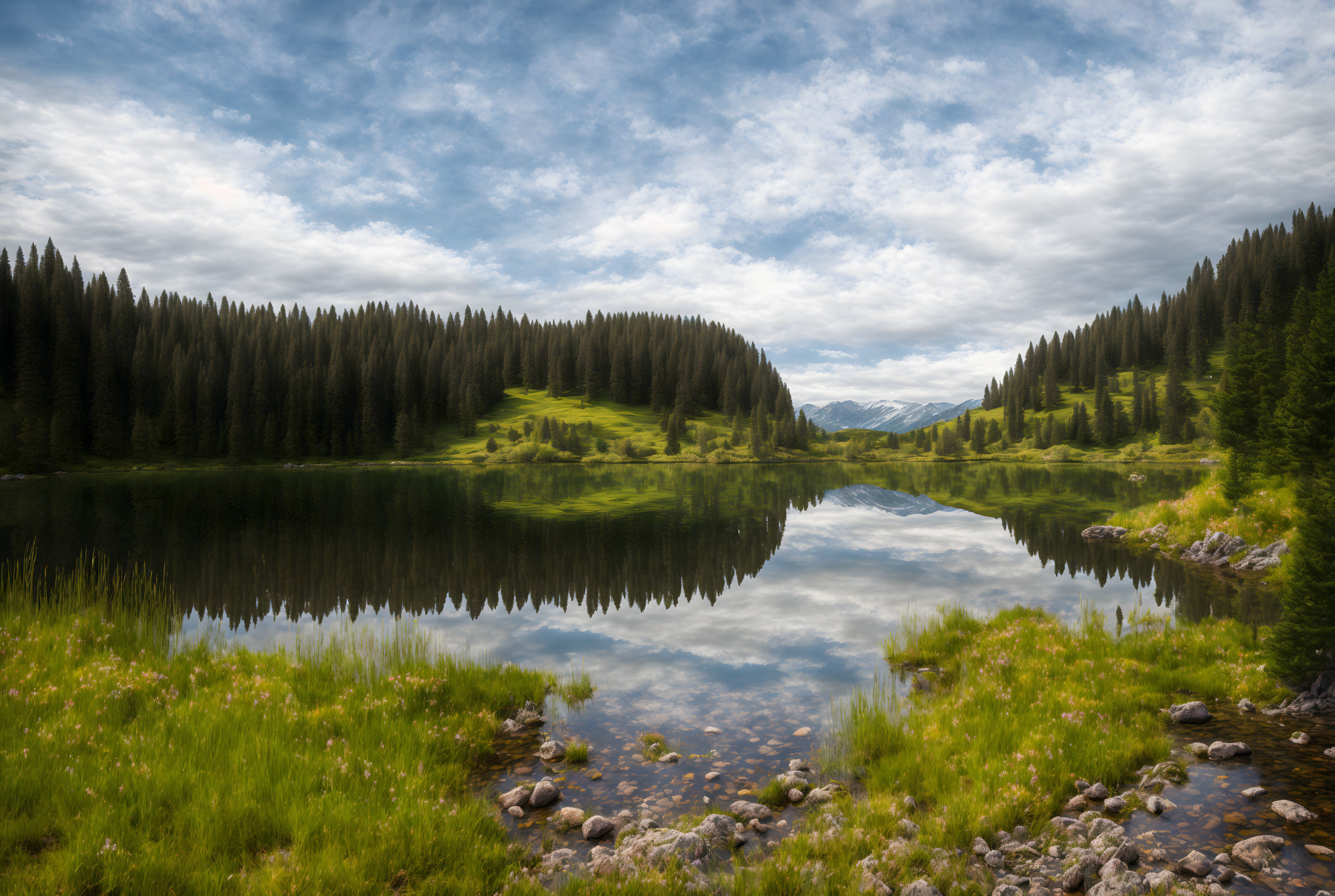 Tranquil mountain lake with pine trees and snow-capped mountains