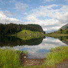 Tranquil mountain lake with pine trees and snow-capped mountains