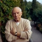 Elderly man sitting at table with drink amid green plants