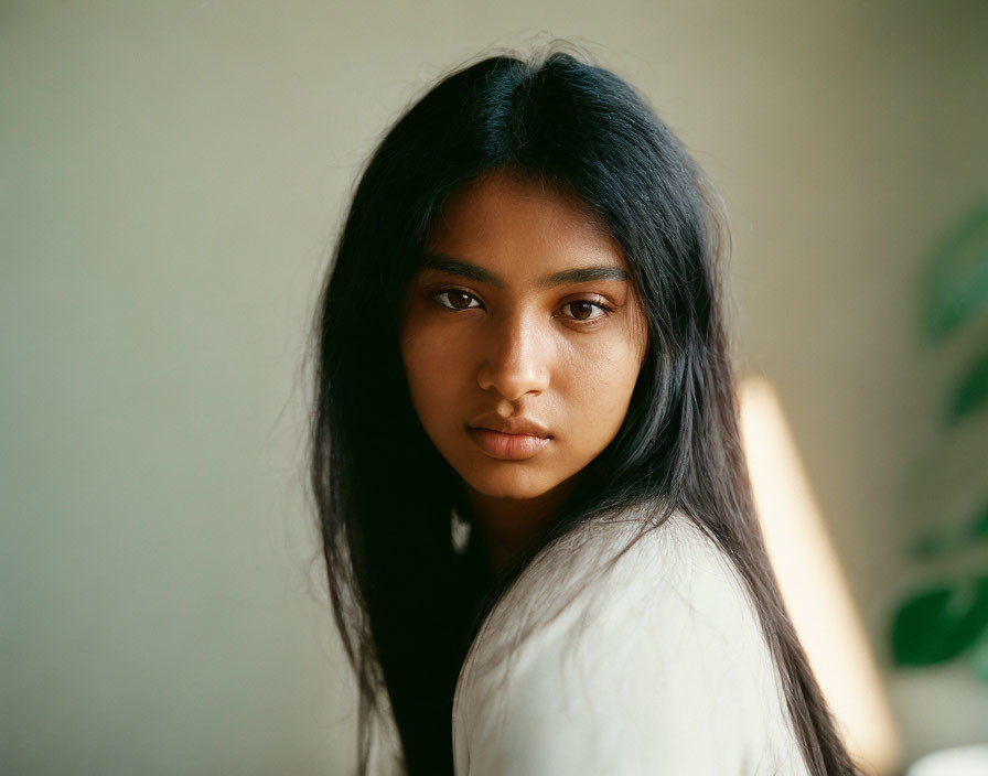 Young woman with long dark hair in white shirt under soft natural light