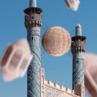 Tall minarets under blue sky with cloud and bush on wire.