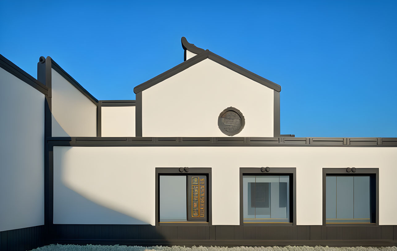 Modern white building with traditional roof and circular window under blue sky