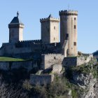 Stone castle with conical roofs on giant tree roots under blue sky