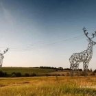 Stylized deer with prominent antlers in serene grassland near glowing futuristic tower