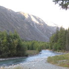 Scenic river flowing through forest to sunlit mountains