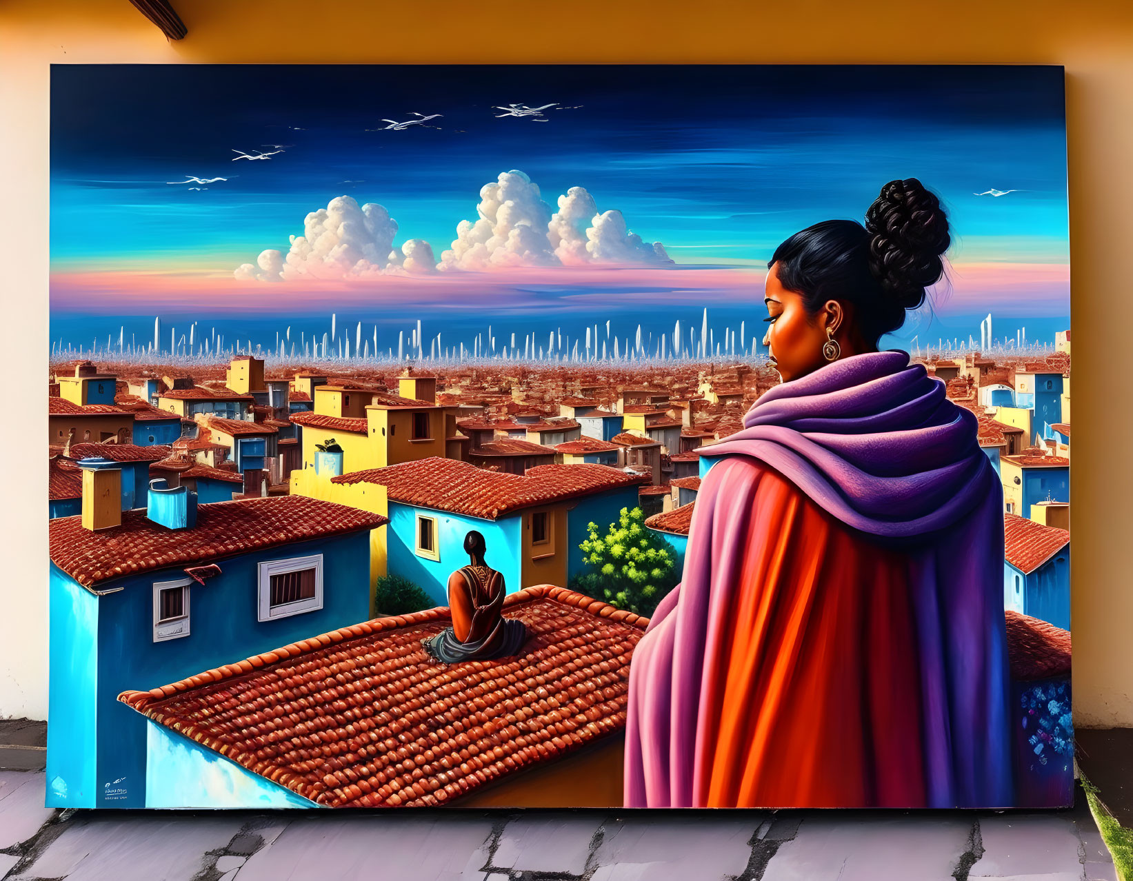 Colorful street art mural featuring woman in shawl, cityscape, blue houses, dramatic sunset sky