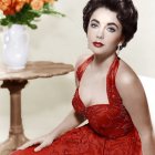 Portrait of woman in red dress with floral embroidery and orange flowers on table