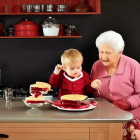 Elderly woman and child enjoying cherry pies at a fruit-filled table