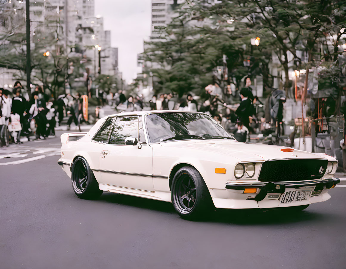 Classic white sports car parked in urban setting with pedestrians.