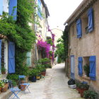 Cobblestone Street with Stone Houses and Flowers Under Blue Sky