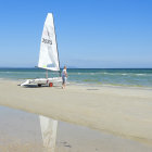 White sailboats on geometric sea under pink and blue sky