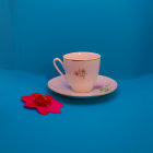 Floral pattern teacups on reflective turquoise surface with scattered petals.