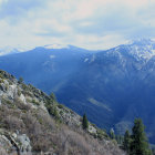 Snow-covered houses on mountainside with frosty trees and snowy peaks