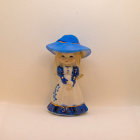 Vintage-inspired blue and white dresses on two women with elegant hats against a beige backdrop