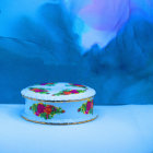 Floral-patterned box on blue surface with floating flowers and soft rainbow.