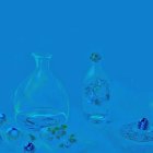 Transparent Bottles with Vine Leaves and Grapes on Blue Background