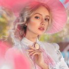 Woman in elegant attire with large pink hat and ruffled blouse among soft pink blossoms