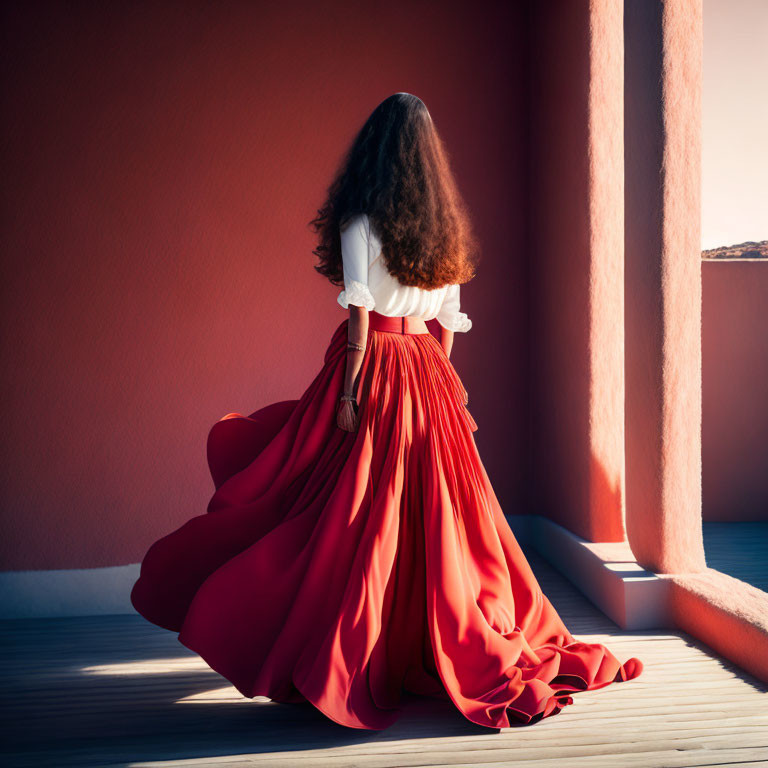 Long-haired woman in red skirt standing in sunlit red corridor