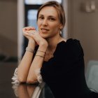 Stylish woman in black dress with red lipstick and pearls poses elegantly