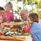 Multigenerational family enjoying homemade pies under a cherry tree