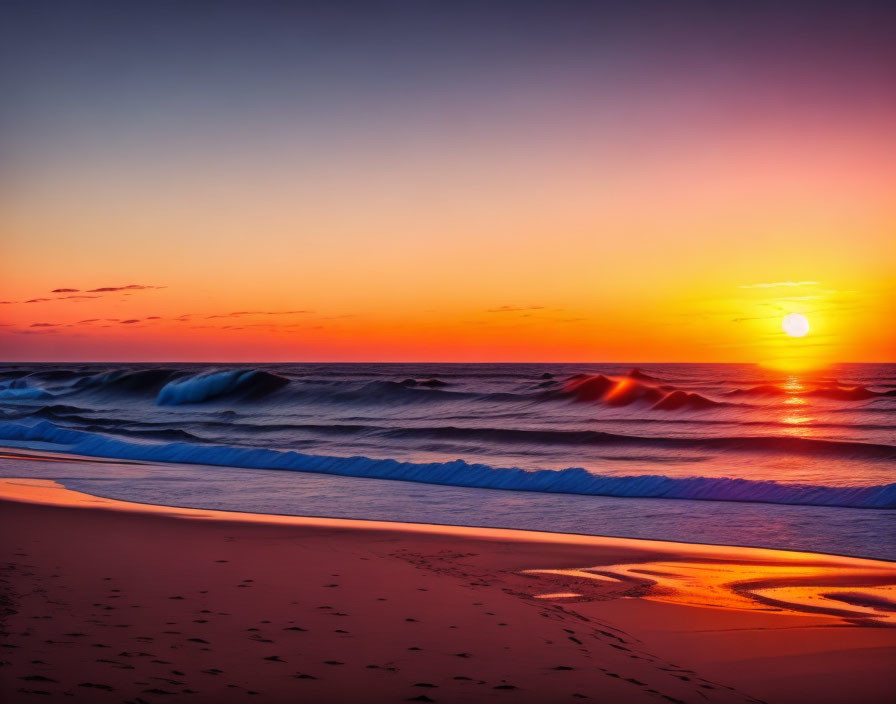 Scenic beach sunset with orange and blue skies, setting sun, and gentle waves on sandy shore