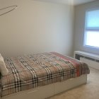 Modern Bedroom with Large Bed, Golden Bedding, Arched Mirror, White Walls, and Natural Light