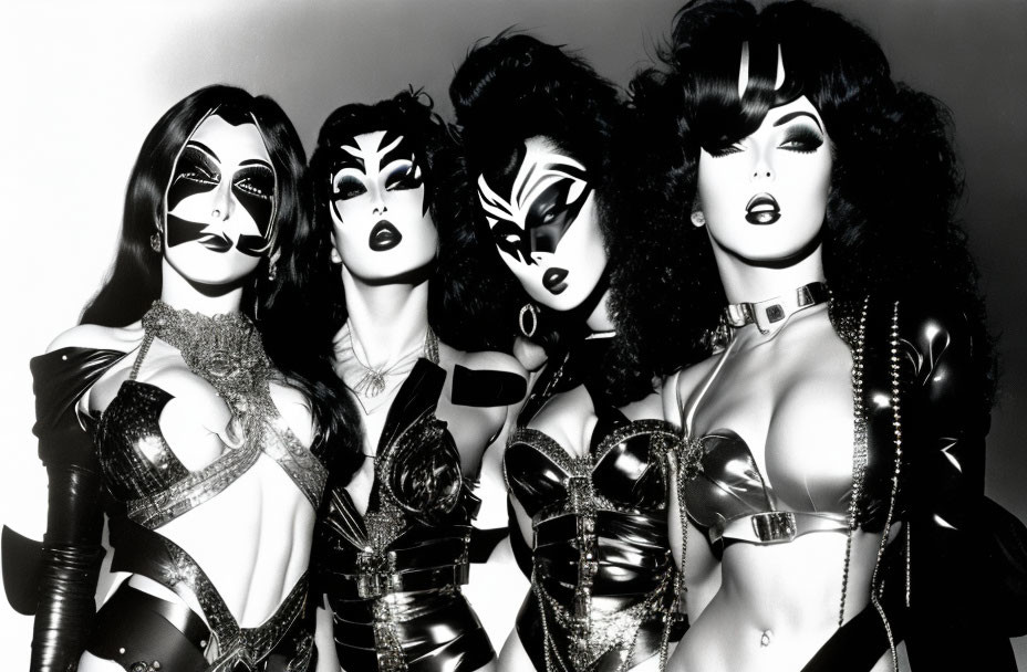 Five individuals in dramatic makeup and elaborate costumes in black and white.