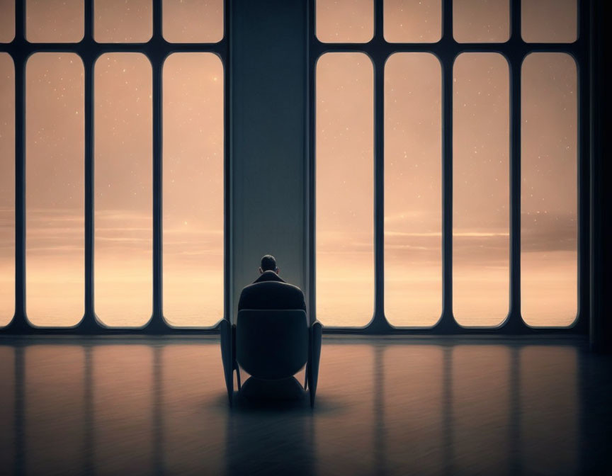 Person sitting in chair by large windows with starry sky view in dimly lit room