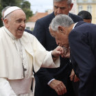 Man in suit kissing ring of smiling religious leader with guards present