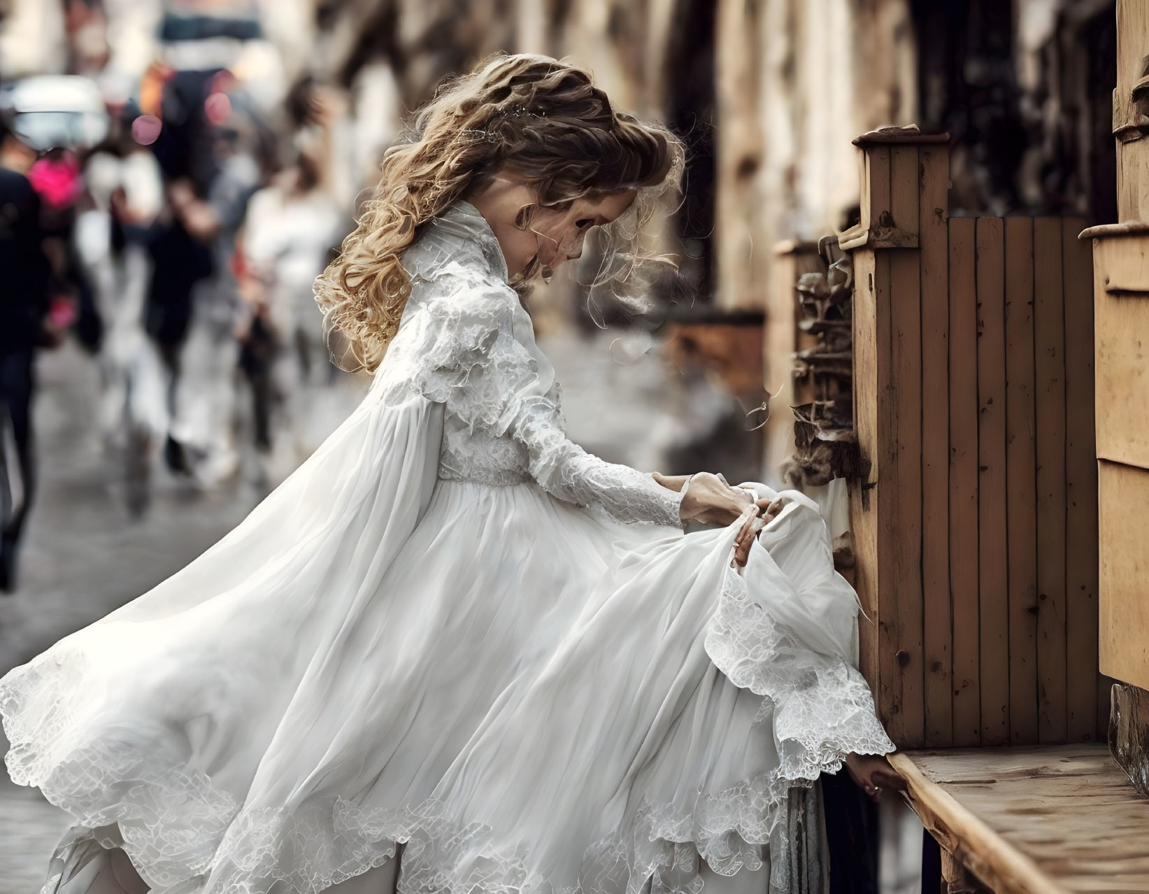 Woman in white vintage dress with lace details adjusting skirt on bustling street