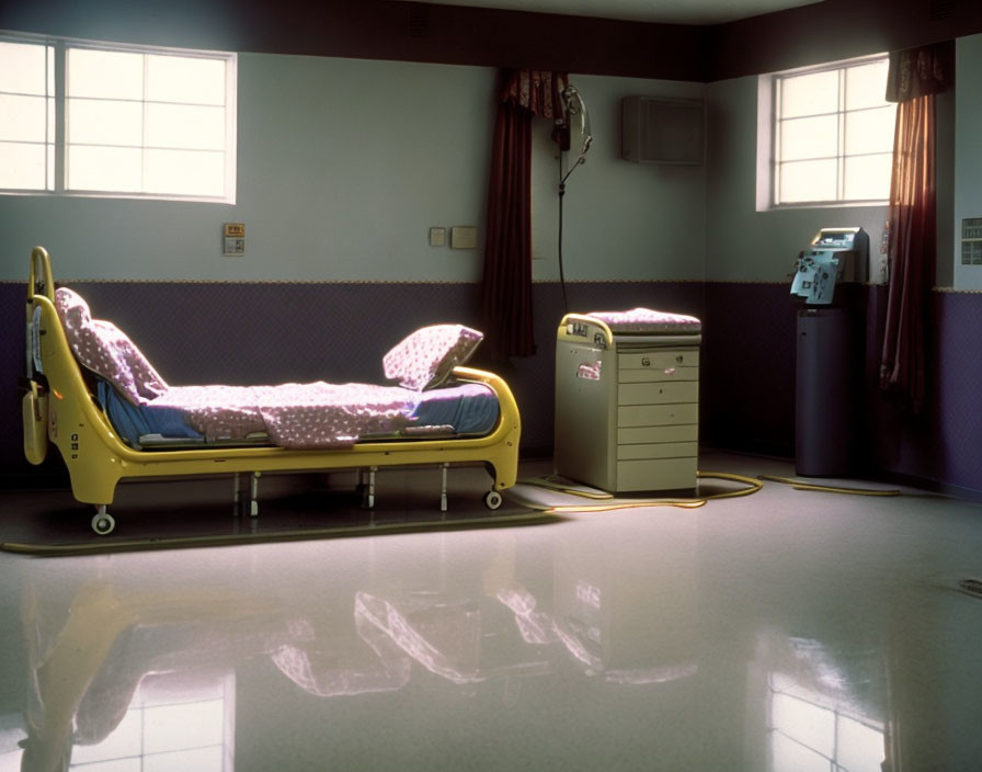 Hospital room with single bed, bedside cabinet, medical equipment, and closed curtains.