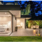 Luxurious outdoor living space with pool, glass walls, and lush greenery at dusk