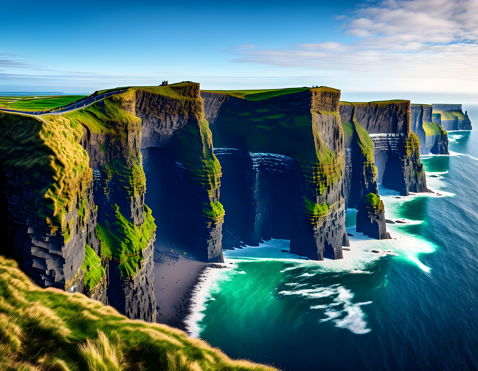 Majestic cliffs with green tops above turquoise sea under blue sky