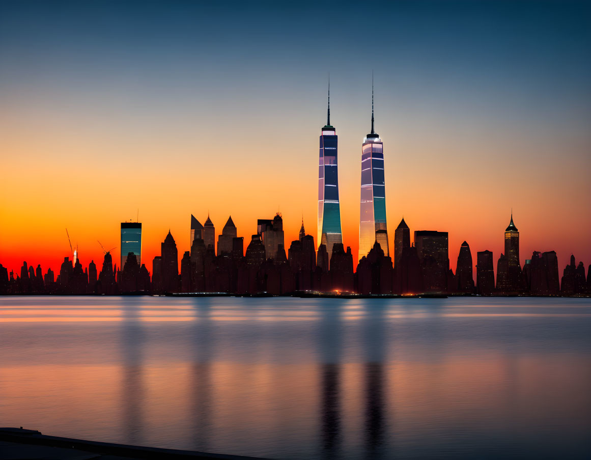 New York City skyline silhouetted at sunset with Twin Towers against orange sky