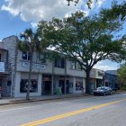 Vibrant street scene with colorful storefronts, vintage cars, and blooming trees