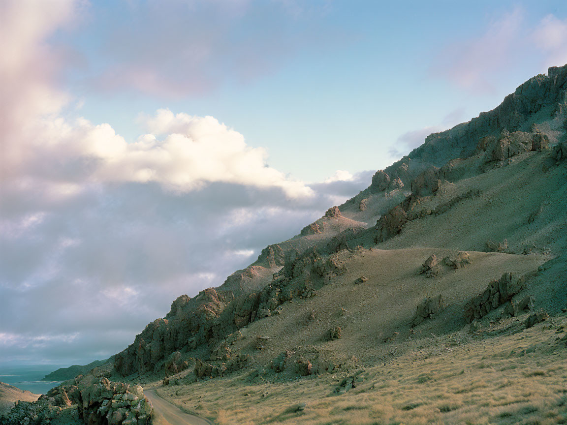 Tranquil landscape of rolling hills and scattered rocks under a soft blue sky