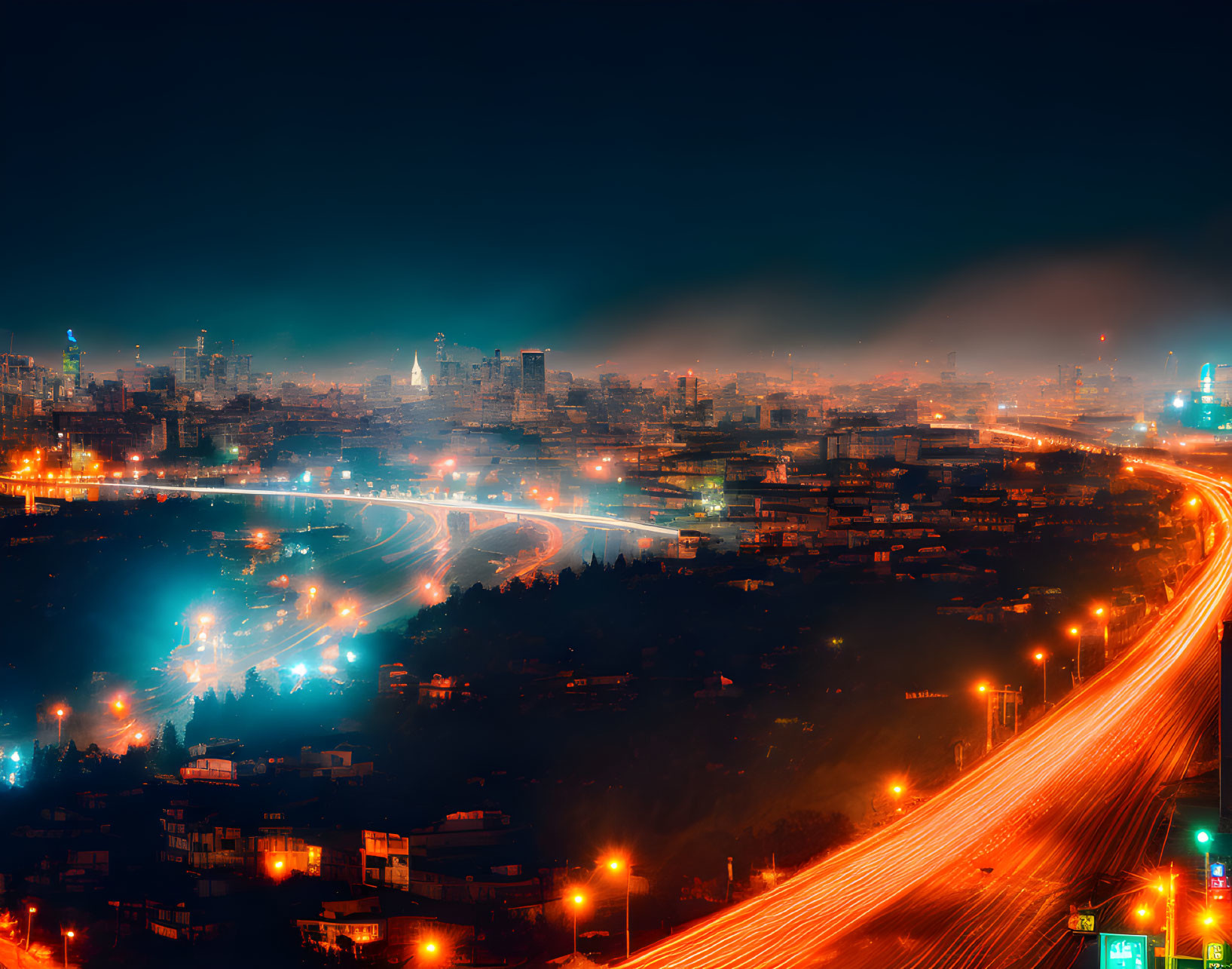 Glowing cityscape with winding highway and illuminated buildings at night