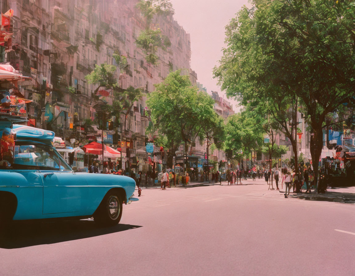 Classic Blue Car on Sunny Street with Pedestrians, Trees, and Red Umbrellas