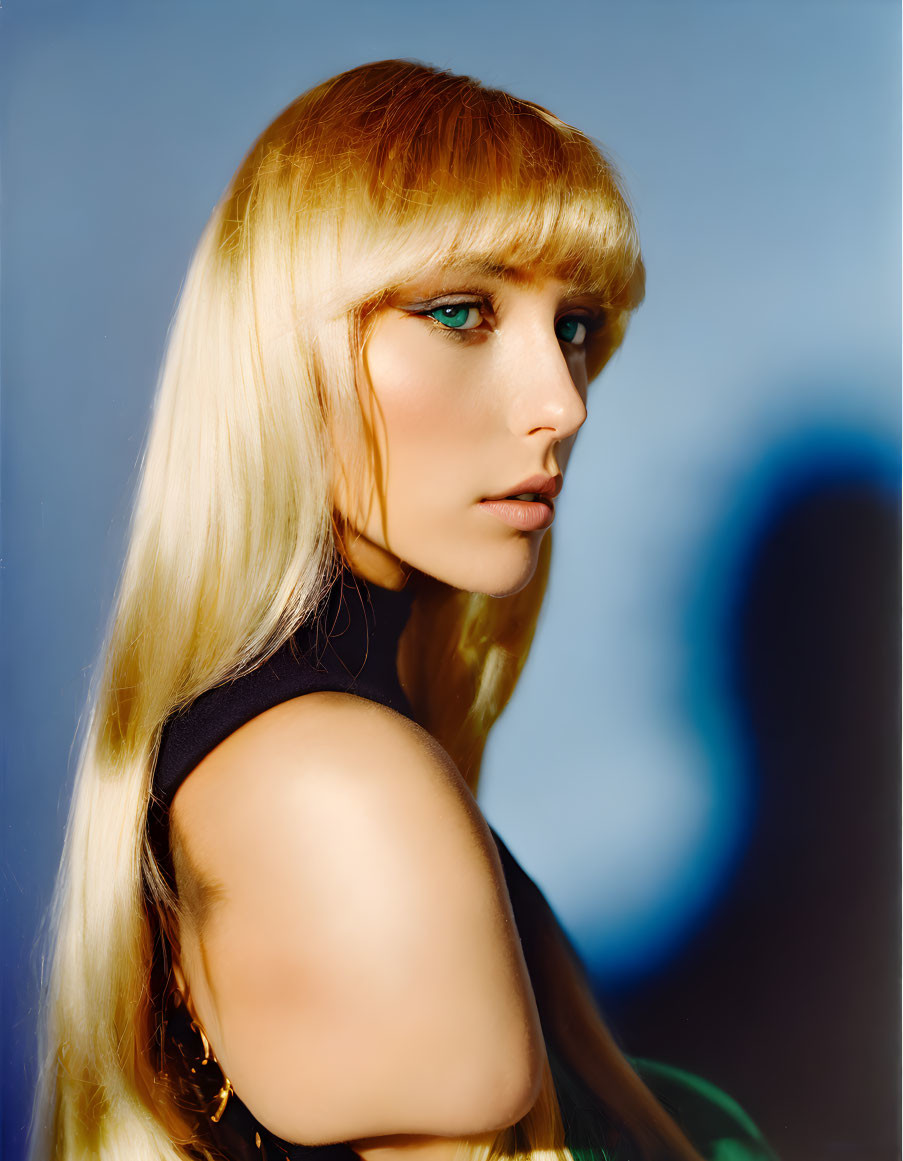 Blonde woman with blue eyes in black top on blue background