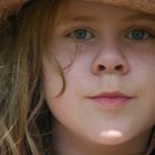 Portrait of person with curly hair, blue eyes, freckles, and smile