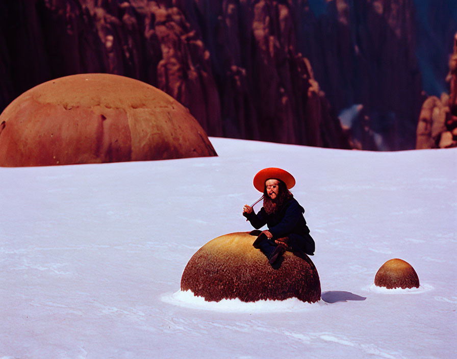 Person in traditional attire on rounded stone in snowy landscape